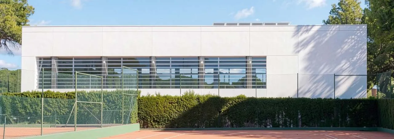 Pabellón deportivo con fachada blanca y pista exterior